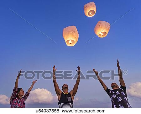 Stock Photo - Young people with illuminated lanterns at sunset. Fotosearch