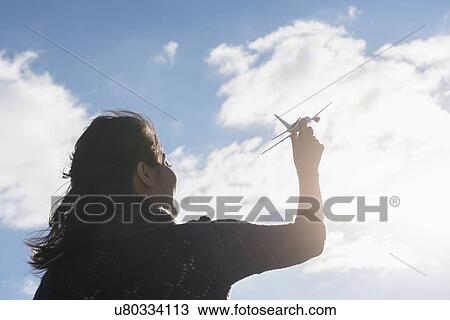Young woman holding model airplane against cloudy sky View Large Photo Image Stock Image - Young woman holding model airplane against cloudy sky. Fotosearch