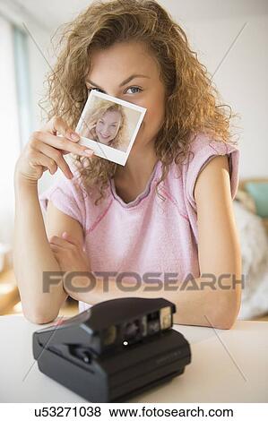 Young woman holding Polaroid photo in front of her face View Large Photo Image Stock Photo - Young woman holding Polaroid photo in front of her face. Fotosearch