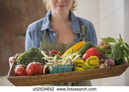 Stock Image - Young woman holding tray with vegetables. Fotosearch