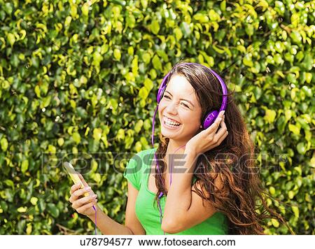 Young woman listening to music and laughing View Large Photo Image Stock Photo - Young woman listening to music and laughing. Fotosearch