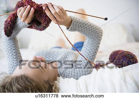 Stock Photo - Young woman lying down and knitting. Fotosearch