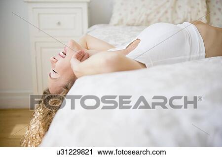 Young woman lying down on bed and laughing View Large Photo Image Stock Image - Young woman lying down on bed and laughing. Fotosearch