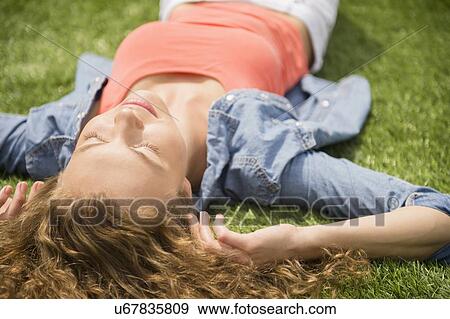 Young woman lying on lawn View Large Photo Image Stock Photo - Young woman lying on lawn. Fotosearch