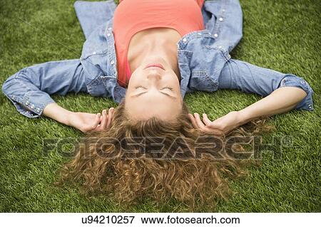 Stock Photo - Young woman lying on lawn. Fotosearch