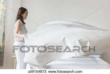 Young woman making bed View Large Photo Image Stock Image - Young woman making bed. Fotosearch