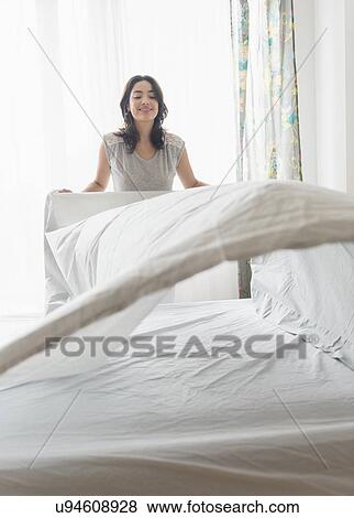 Young woman making bed View Large Photo Image Stock Photo - Young woman making bed. Fotosearch