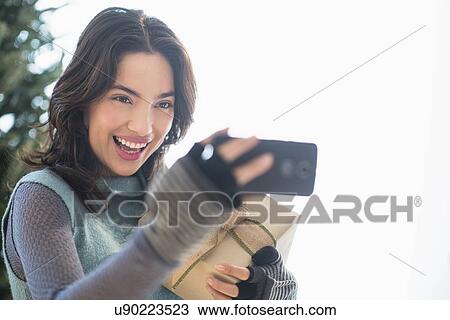 Young woman taking selfie with mobile phone View Large Photo Image Stock Image - Young woman taking selfie with mobile phone. Fotosearch