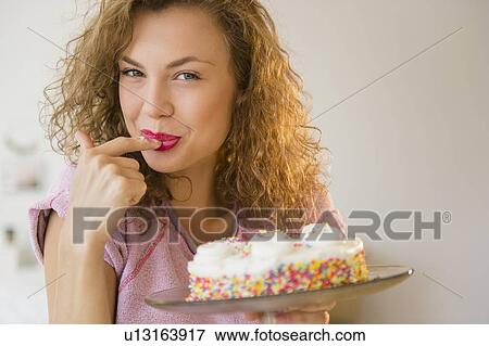 Stock Photo - Young woman tasting birthday cake. Fotosearch