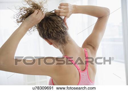 Stock Image - Young woman tying hair. Fotosearch