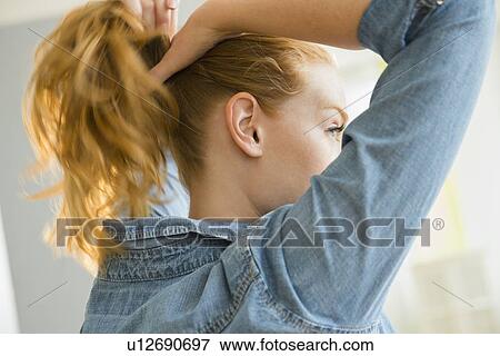 Young woman tying hair View Large Photo Image Stock Photo - Young woman tying hair. Fotosearch