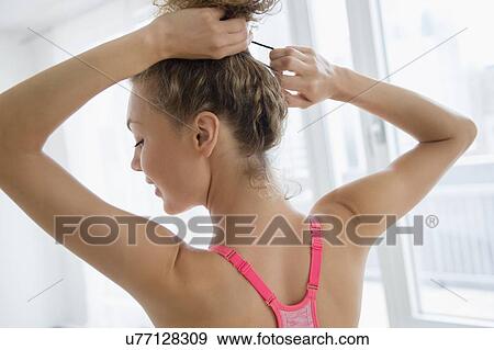 Stock Photo - Young woman tying hair. Fotosearch