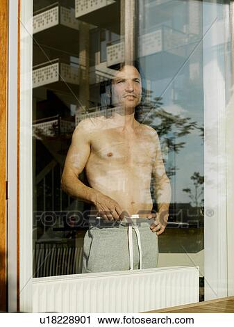 Bare-chested man standing at window View Large Photo Image Stock Image - Bare-chested man standing at window. Fotosearch