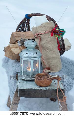Stock Image - Basket, lantern, wooden cup in snow. Fotosearch