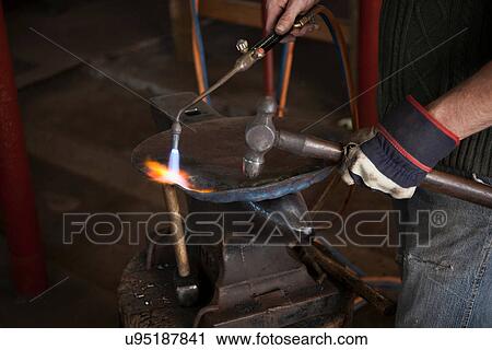 Stock Image - Blacksmith at work in shop. Fotosearch