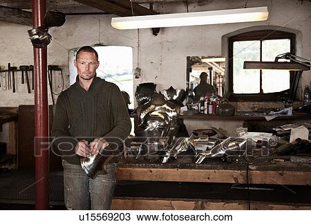 Stock Image - Blacksmith with armor in shop. Fotosearch