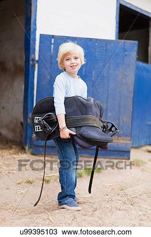 Boy carrying horse saddle View Large Photo Image Stock Image - Boy carrying horse saddle. Fotosearch