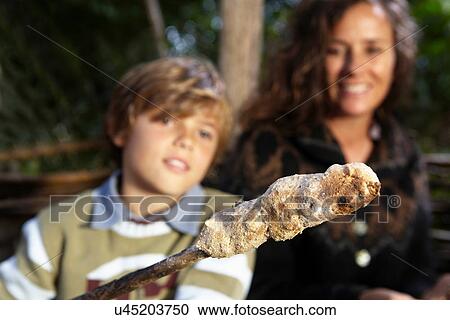 Stock Image - Boy cooking bread over fire. Fotosearch
