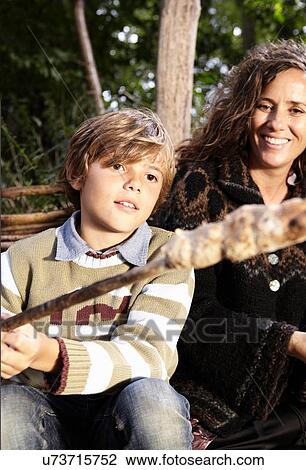Stock Image - Boy cooking bread over fire. Fotosearch