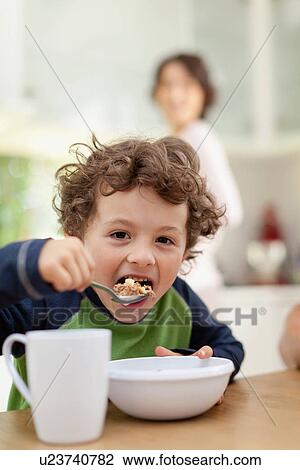 Boy eating breakfast in kitchen View Large Photo Image Stock Image - Boy eating breakfast in kitchen. Fotosearch