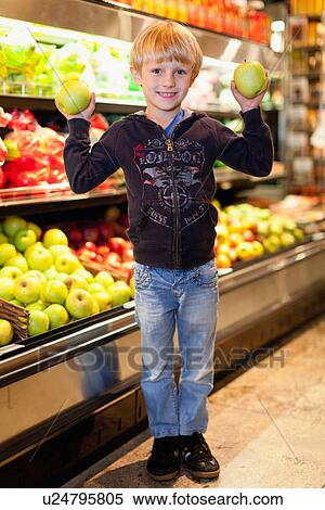 Stock Photography - Boy holding fruit at grocery store. Fotosearch