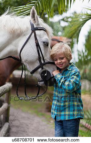 Stock Image - Boy hugging horse in yard. Fotosearch