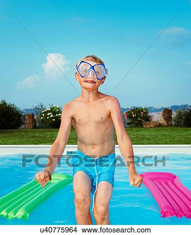 Picture - Boy in mask jumping into swimming pool. Fotosearch