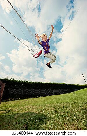 Picture - Boy jumping off swing in backyard. Fotosearch