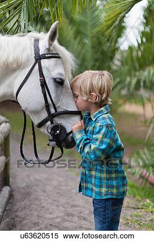 Stock Photography - Boy kissing horse in yard. Fotosearch
