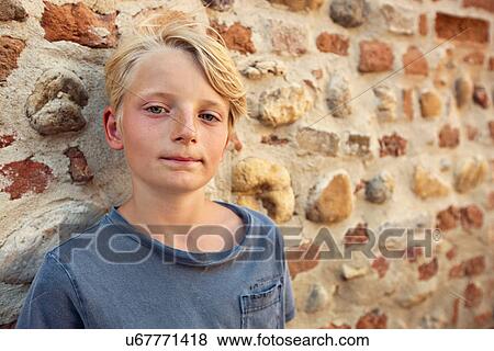 Stock Photo - Boy leaning against stone wall. Fotosearch