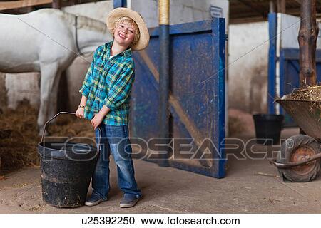 Boy lugging bucket in stable View Large Photo Image Stock Image - Boy lugging bucket in stable. Fotosearch