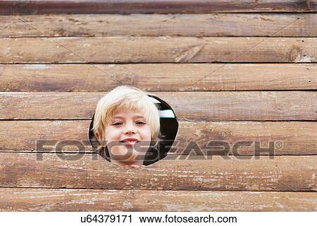 Stock Image - Boy peeking through hole in playhouse. Fotosearch