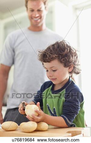 Picture - Boy peeling potatoes in kitchen. Fotosearch