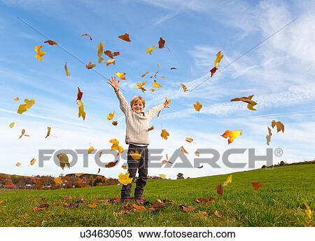 Stock Photography - Boy playing in fall leaves. Fotosearch