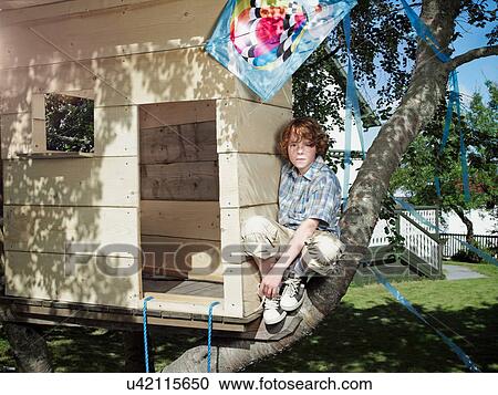 Stock Image - Boy playing in treehouse. Fotosearch