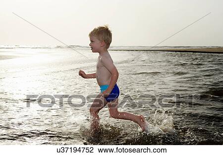 Boy playing in water at beach View Large Photo Image Stock Image - Boy playing in water at beach. Fotosearch
