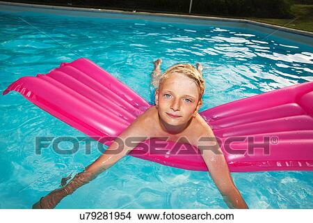 Boy playing on raft in swimming pool View Large Photo Image Picture - Boy playing on raft in swimming pool. Fotosearch