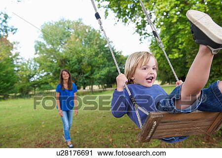 Boy playing on swing in backyard View Large Photo Image Stock Image - Boy playing on swing in backyard. Fotosearch