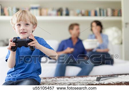 Boy playing video games in living room View Large Photo Image Stock Photo - Boy playing video games in living room. Fotosearch