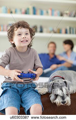 Boy playing video games in living room View Large Photo Image Stock Photo - Boy playing video games in living room. Fotosearch