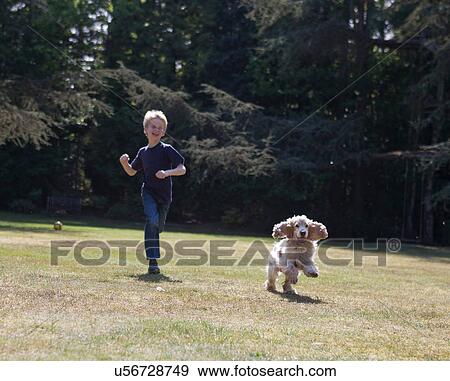 Stock Photo - Boy playing with dog in backyard. Fotosearch