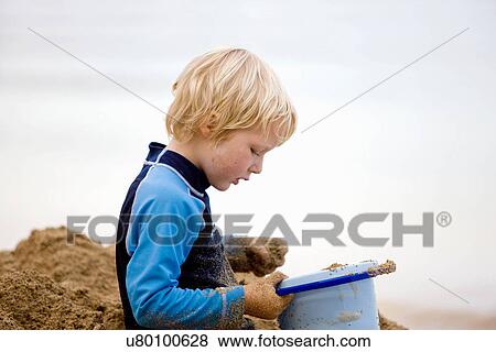 Boy playing with sand on beach View Large Photo Image Stock Photo - Boy playing with sand on beach. Fotosearch