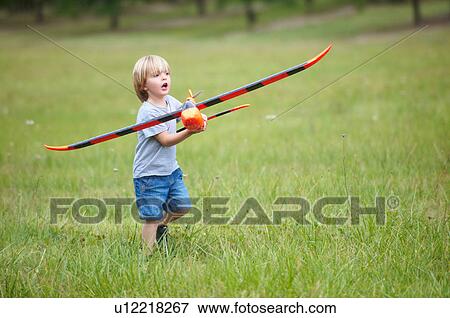 Stock Photo - Boy playing with toy airplane outdoors. Fotosearch
