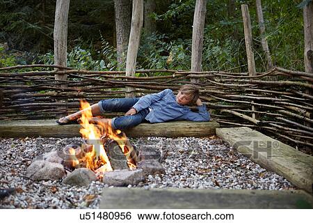 Boy relaxing by fire outdoors View Large Photo Image Stock Photograph - Boy relaxing by fire outdoors. Fotosearch