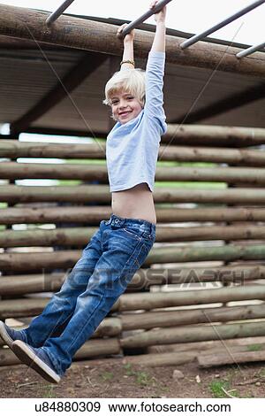 Boy swinging from monkey bars View Large Photo Image Stock Photo - Boy swinging from monkey bars. Fotosearch