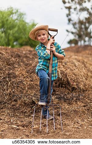 Stock Photography - Boy using pitchfork in haystack. Fotosearch