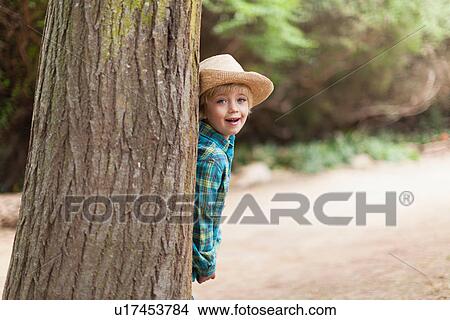 Boy wearing cowboy hat behind tree View Large Photo Image Picture - Boy wearing cowboy hat behind tree. Fotosearch