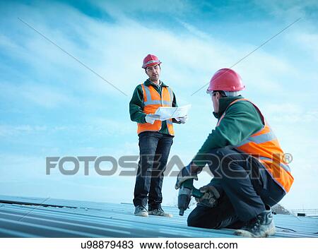 Building foreman holding plans as workman insulates factory roof View Large Photo Image Stock Image - Building foreman holding plans as workman insulates factory roof. Fotosearch