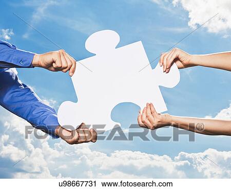 Stock Image - Business people grabbing puzzle piece. Fotosearch