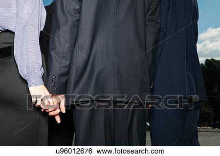 Business people secretly holding hands View Large Photo Image Stock Photograph - Business people secretly holding hands. Fotosearch
